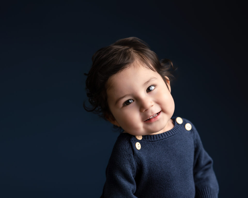 true toddler child playfully smiling on a cobalt blue backdrop