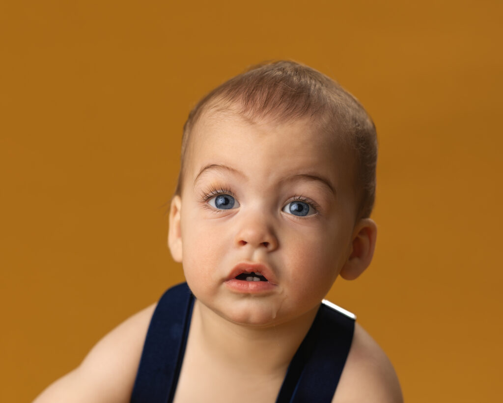 young boy portrait on yellow backdrop with big blue eyes