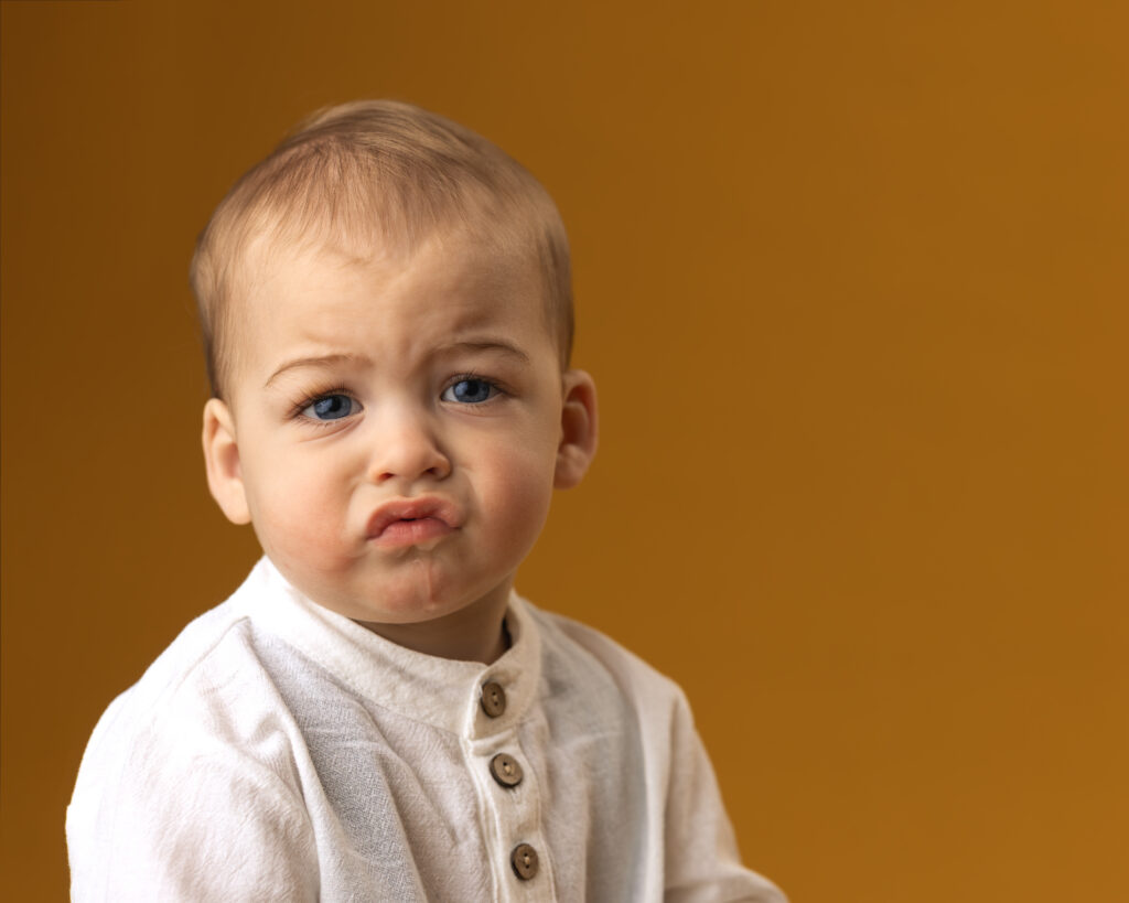 young boy with big frown on yellow backdrop
