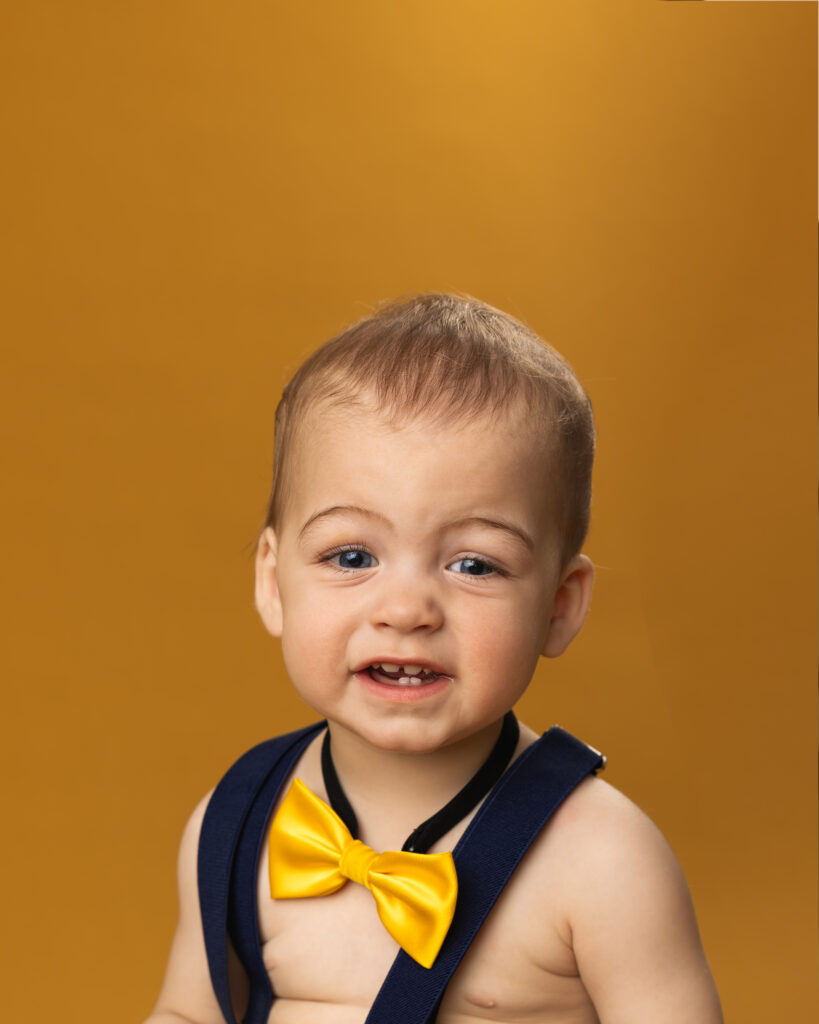 young boy with toothy smile on yellow backdrop