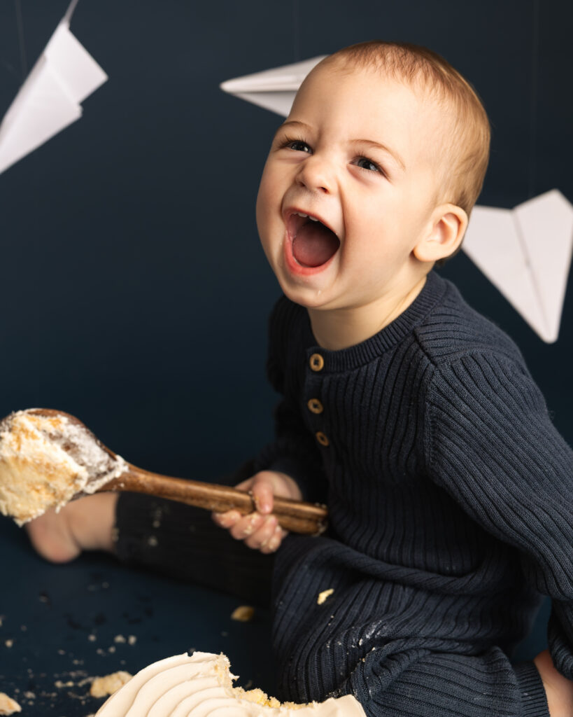 young boy laughing as he smashes a cake
