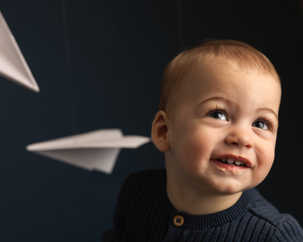 close up image of a little boy smiling on deep blue backdrop