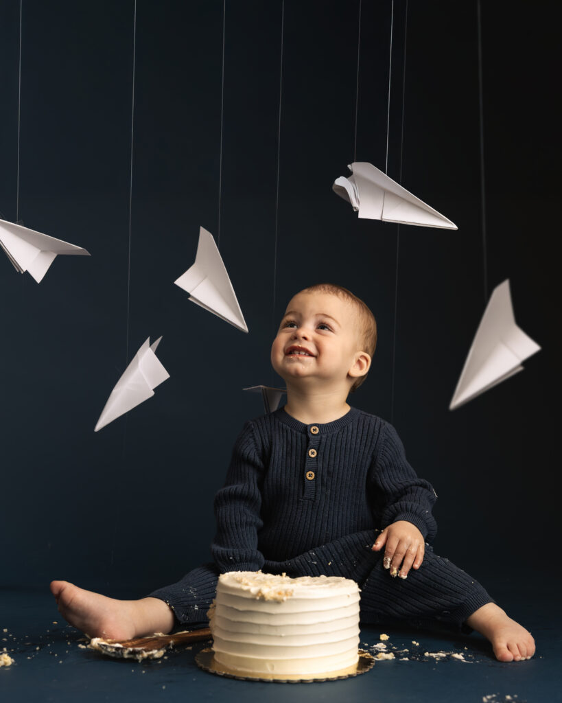 smiling little boy at an aviation themed studio cake smash session